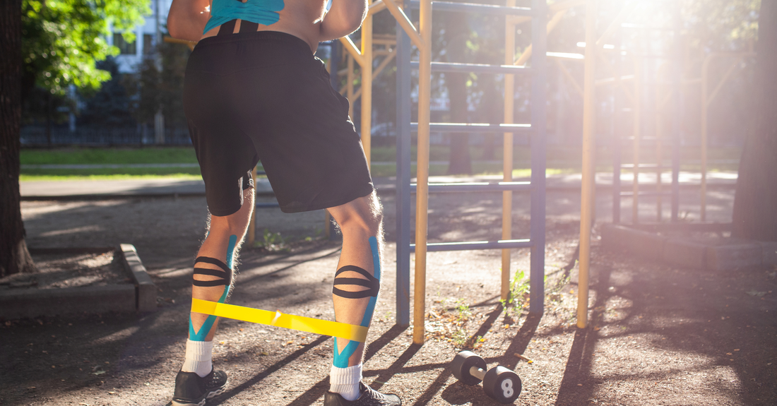 Athlete performing resistance band squats outdoors with kinesiology tape on legs