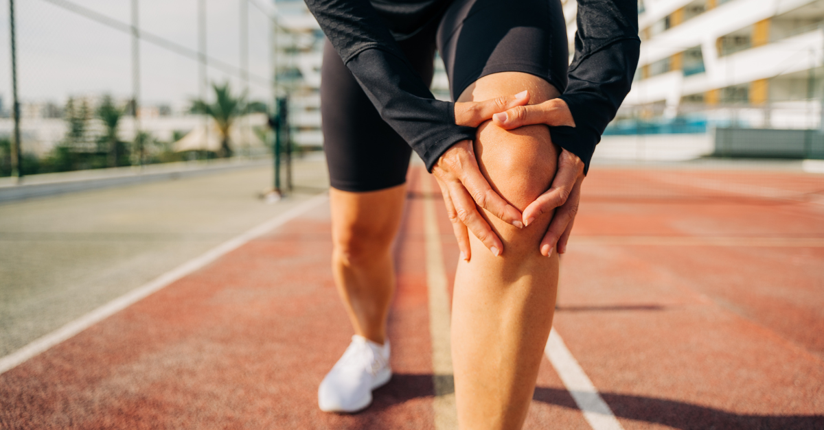 Athlete holding their knee in pain on a running track